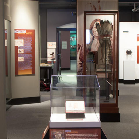 visitors in wide Wiyohpiyata gallery with large color native american drawings.