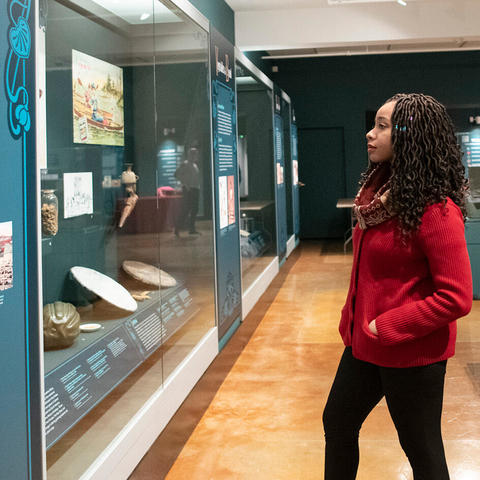 woman in long gallery looks at display.