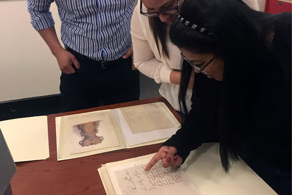 persons leaning over nineteenth century documents in Peabody Museum Archives Department