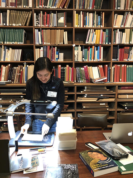 Woman standing in a library, using a scanner