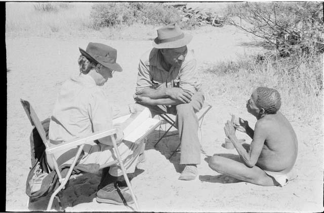 A man and woman sit in lawn chairs talking to a third person sitting on the ground