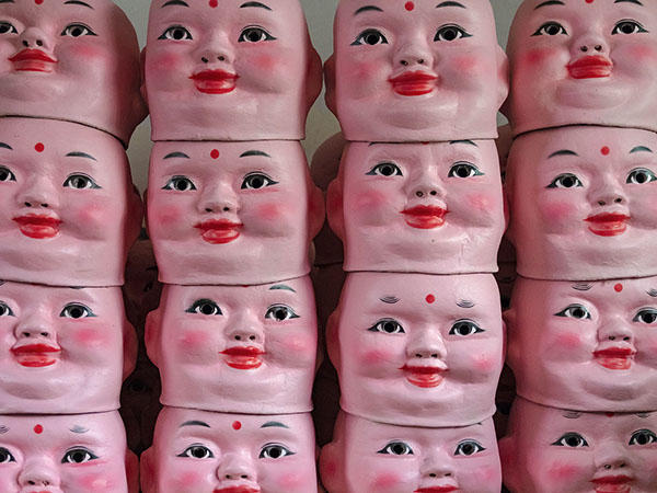 stack of boy doll head masks.