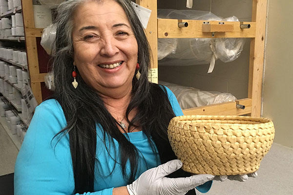 smiling woman holds basket in collections area.