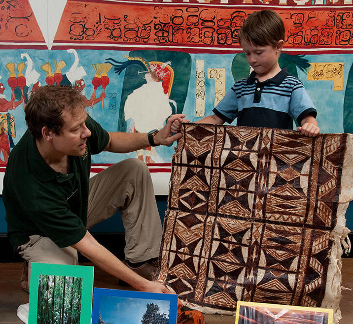 educator and student hold textile in gallery during class.