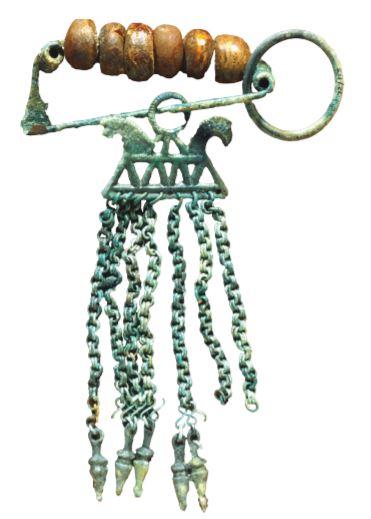 A green rusted fibula with wooden beading. It has a safety pin component which hold the wooden beads on top and a decorative tassel on the bottom.