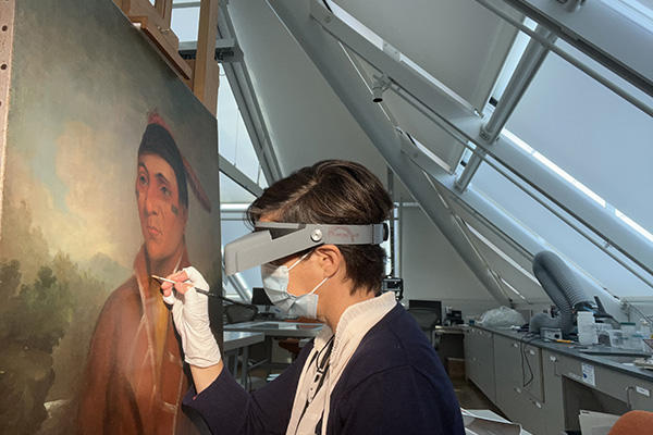 Conservator cleaning a painting