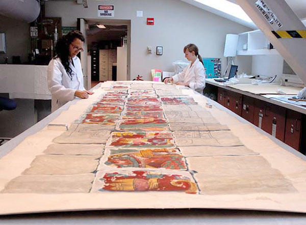 Two women working on cleaning a large watercolor