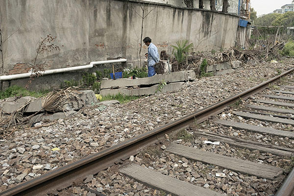 railroad tracks with person away from them toward trash.