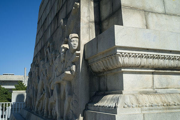 corner of structure with bas relief sculpting of soldiers and decorations.