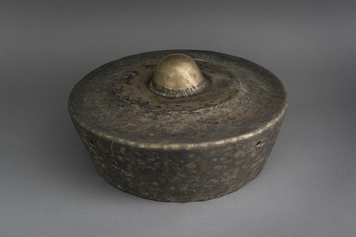 brass gong with domed knob on top.