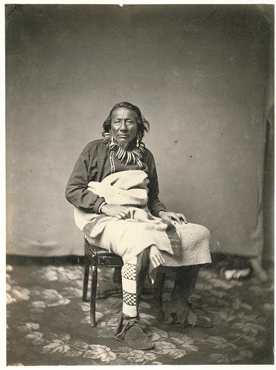 portrait of a seated man wearing traditional native american dress