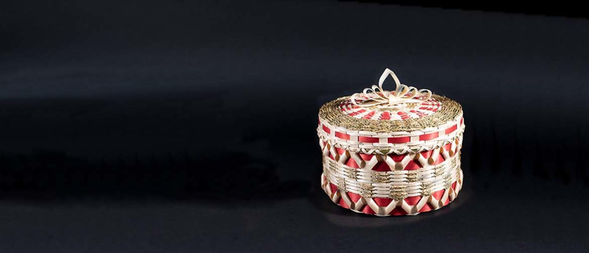 A red and white woven basket shines in the center of the frame against a black background.