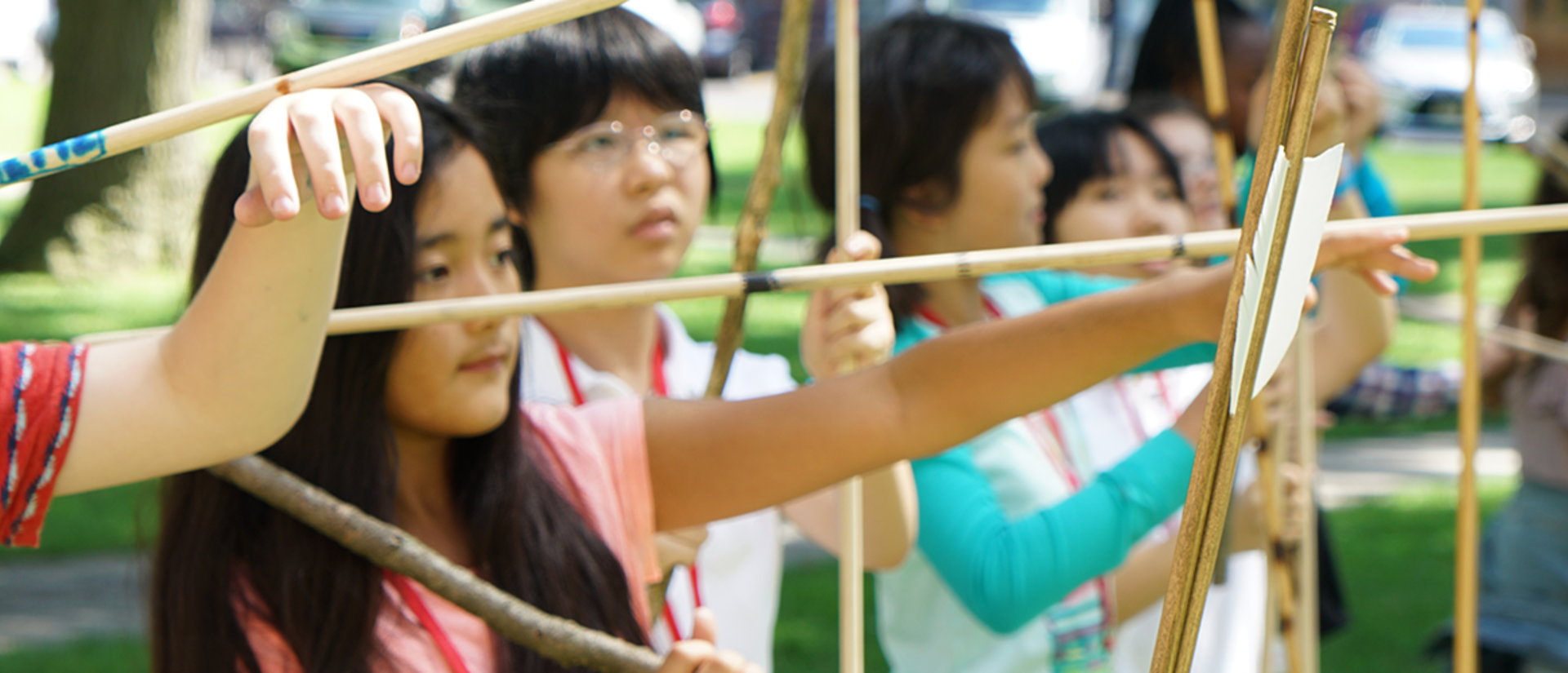 kids prepare to launch spears with atlatls outdoors.