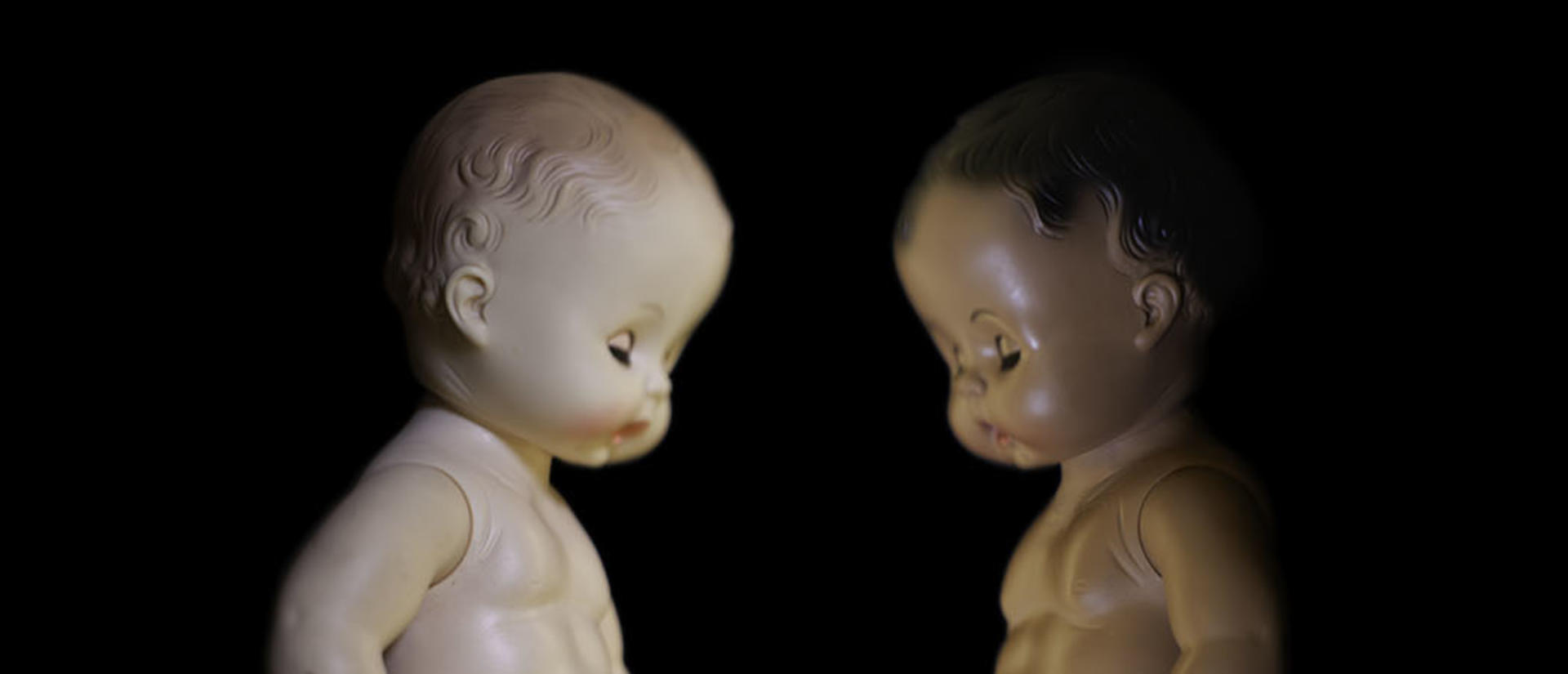 two baby dolls face each other; one is black and one is white.