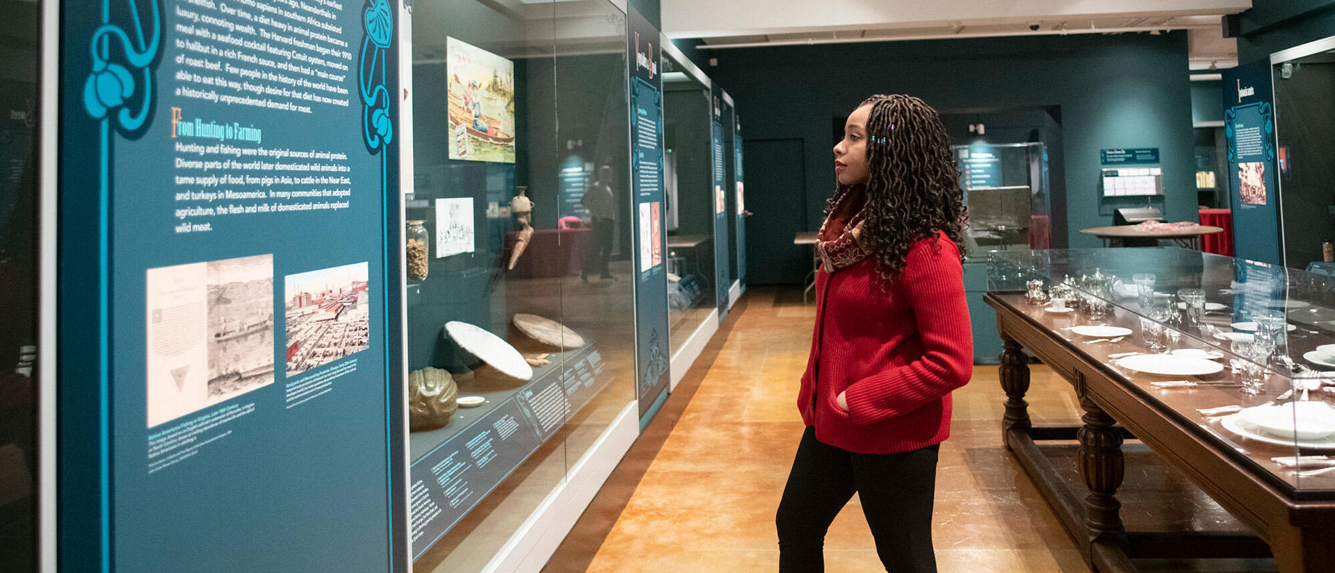woman in long gallery looks at display.