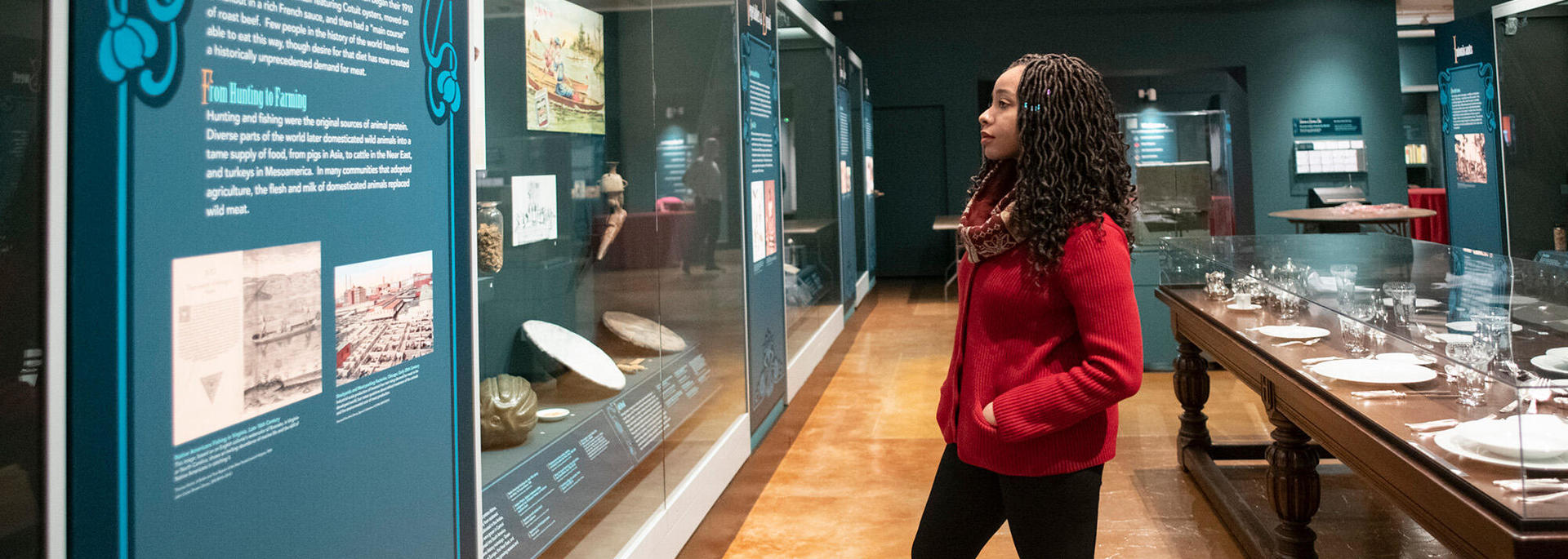 woman in long gallery looks at display.