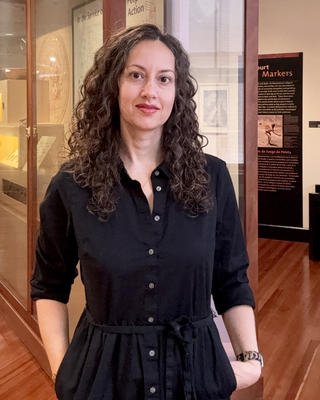 Woman with curly hair standing in gallery wearing a black dress