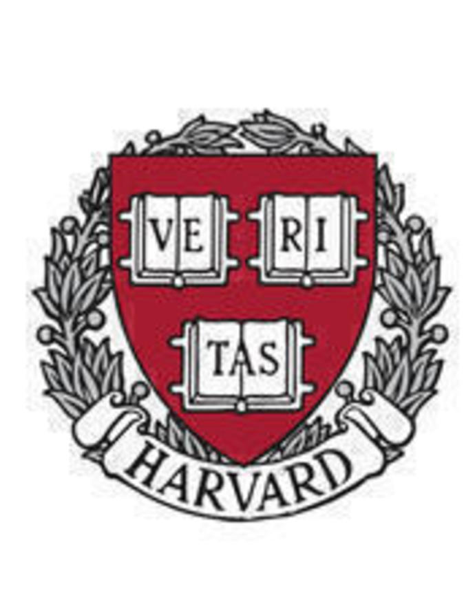 A crimson shield has the word Veritas spelled out across three open books. It is surrounded by a wreath that says Harvard on the bottom.