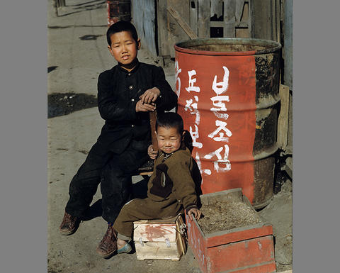 2 children next to a barrel with korean writing on it.