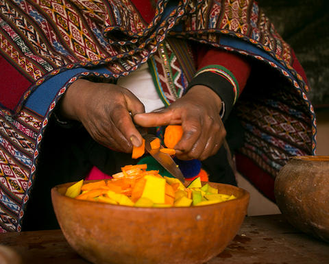 peruvian hands over bowl of food.