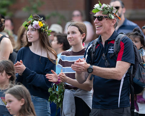 audience wearing flower crowns outside museum applaud.